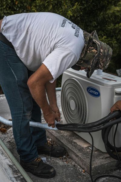 HVAC technician installing an air conditioning condenser unit at a residential property